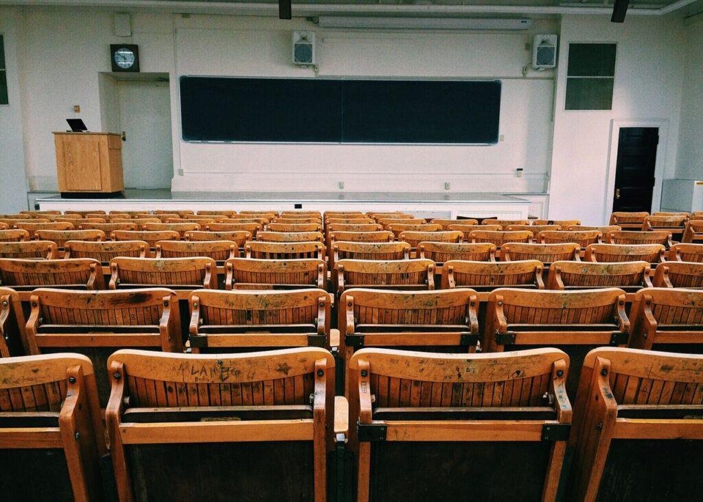 University lecture hall with rows of wooden seats.
